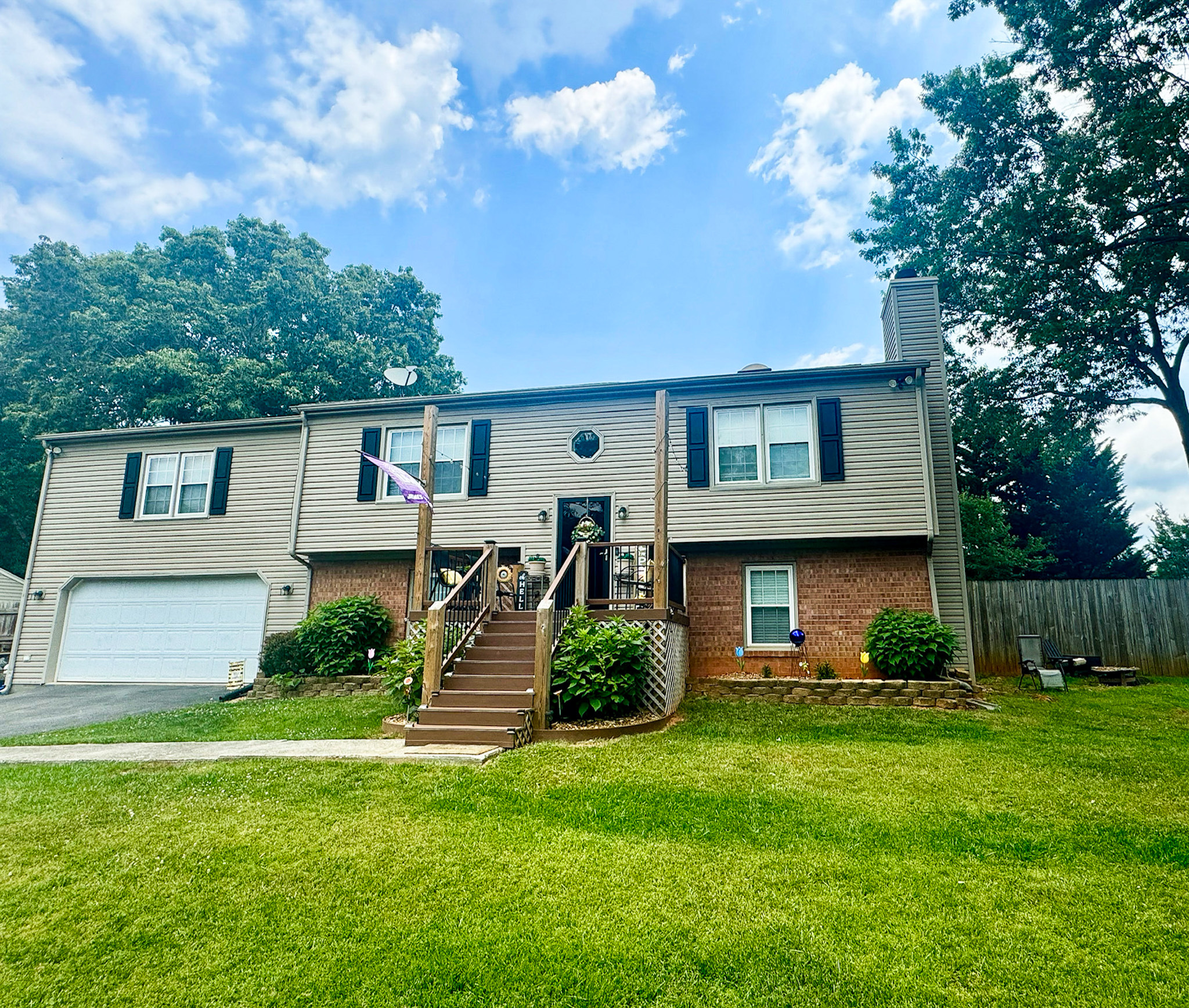 Two‑story split‑foyer house with light brick siding, black shutters, a central staircase to the front door, and a two‑car garage on a green lawn belonging to Sponsored Residential Providers Anthony Barnes and Demita Taylor in Forest, Virginia.