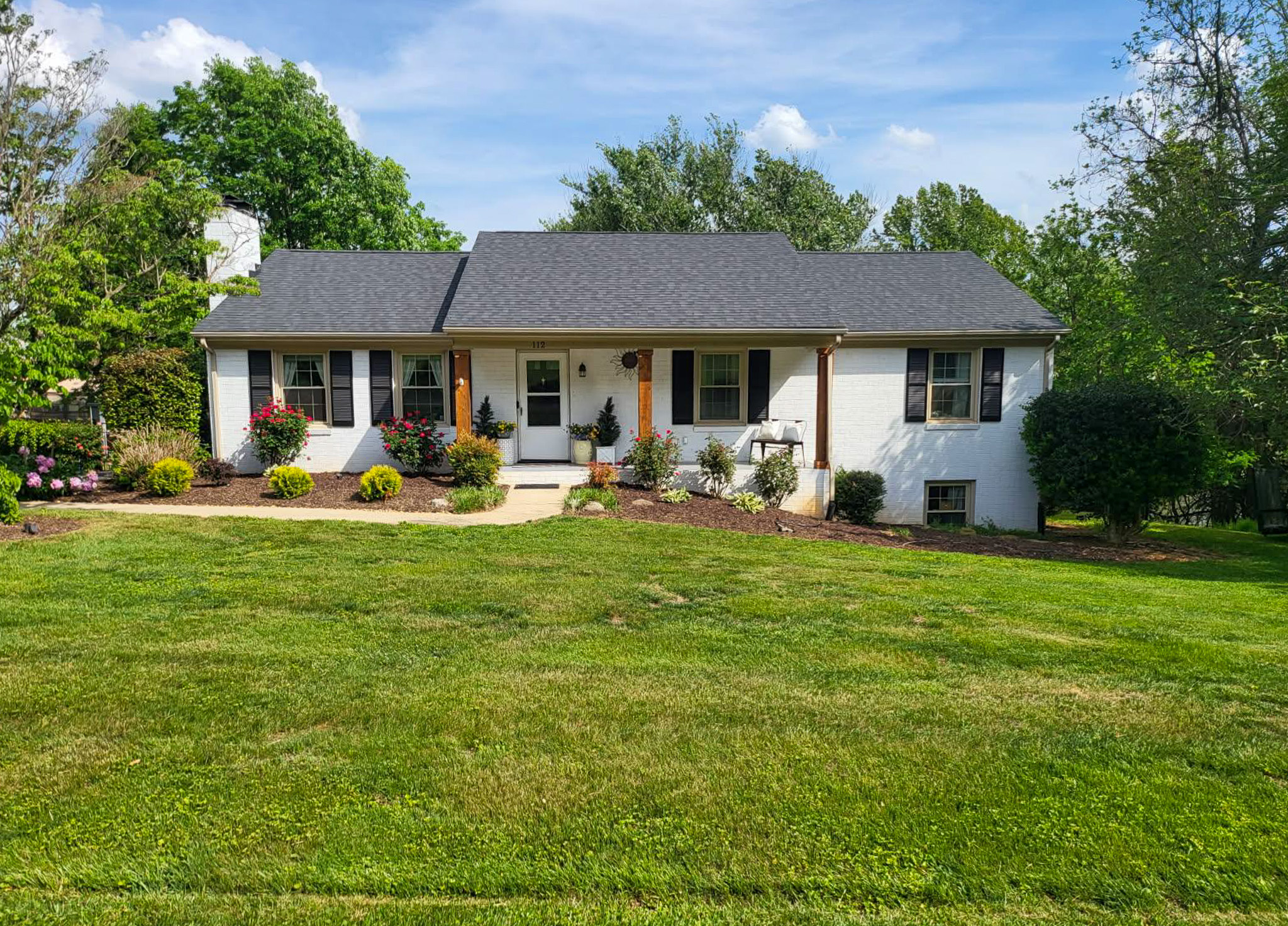 Single-story white house with a front porch and a large green lawn on a sunny day belonging to sponsored residential providers Scott and Tedra Flanders in Lynchburg, Virginia.