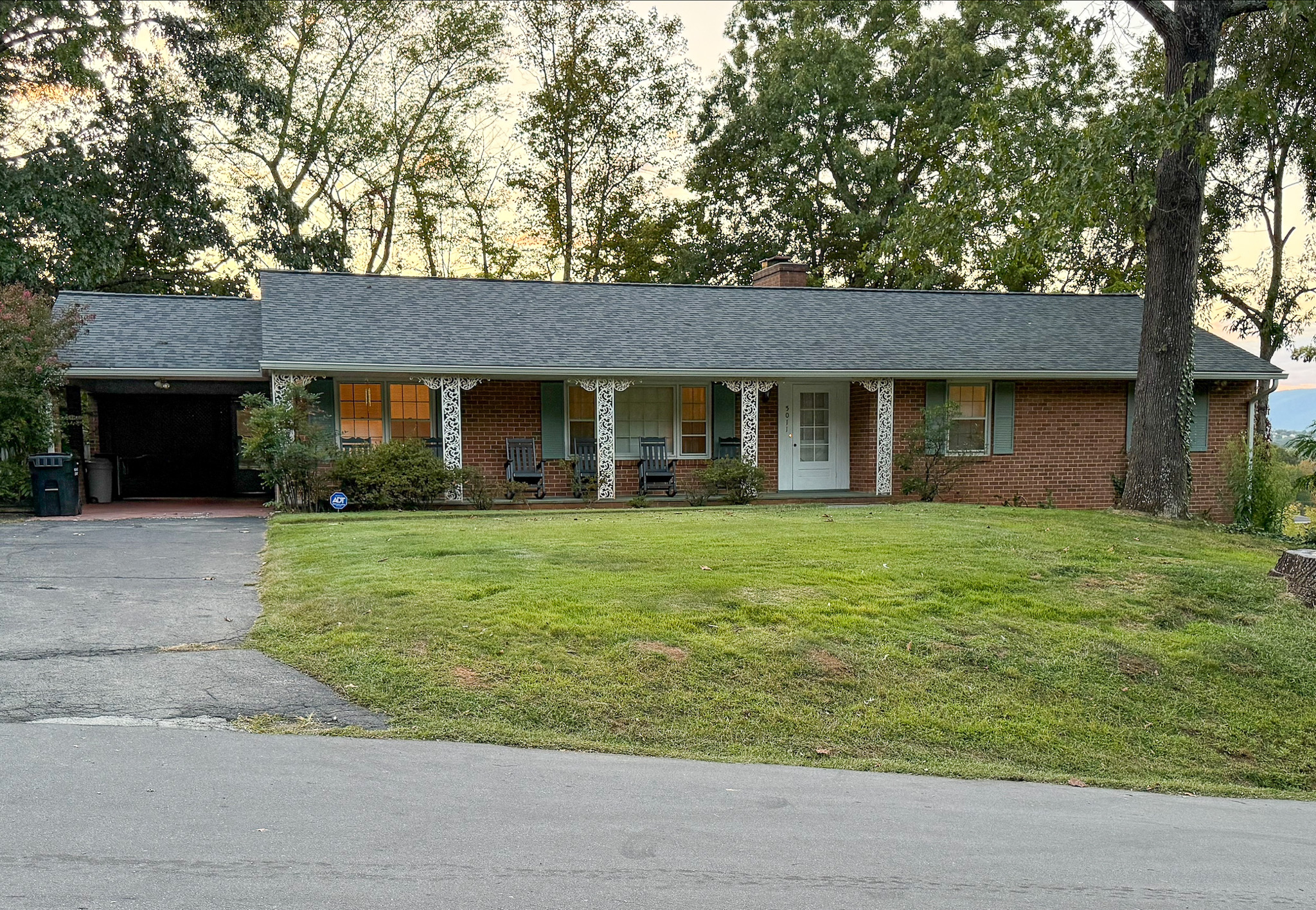 A one‑story brick house with a covered carport, white columns along the front porch, and a large grassy yard facing the street belonging to Group Home Provider Tina Langhorn in Roanoke, Virginia.