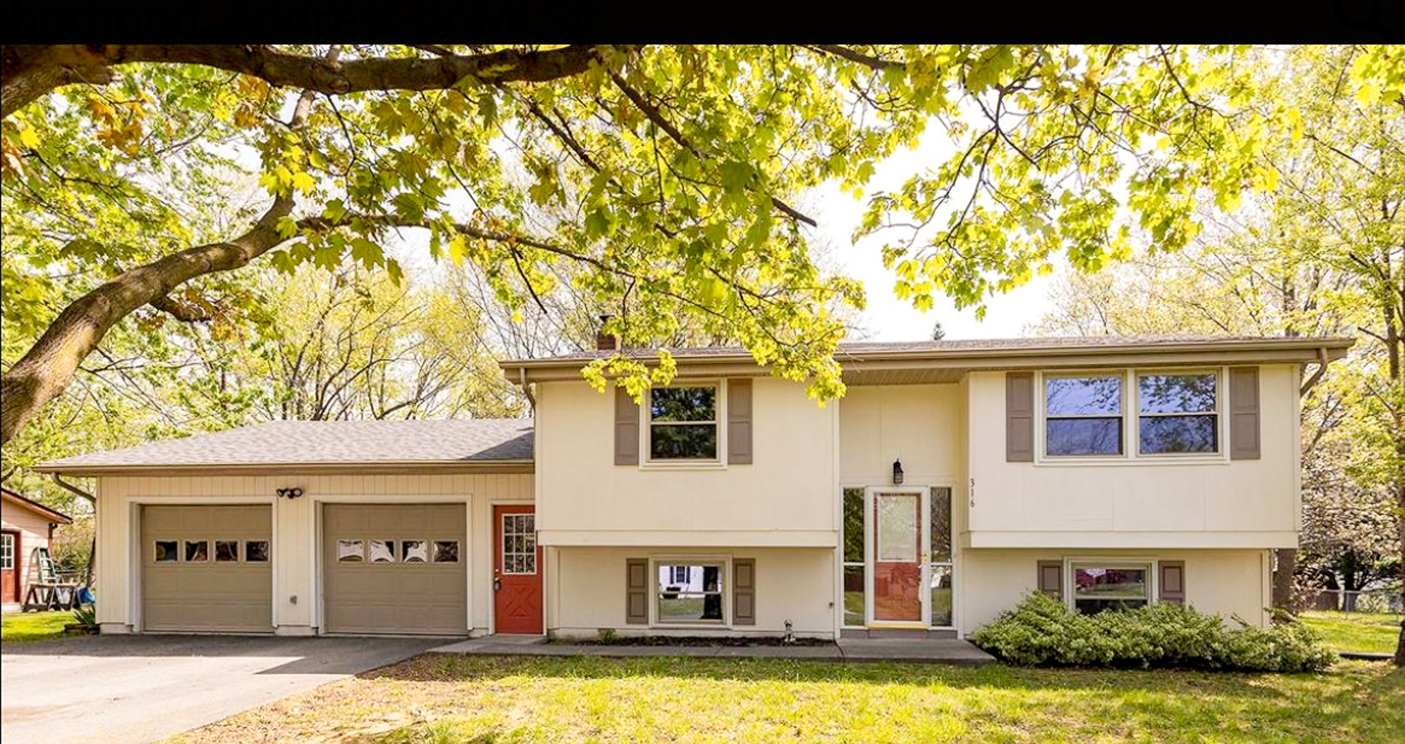 Two‑story split‑level home with an attached garage, light siding, red door, and large front windows beneath leafy trees belonging to Sponsored Residential Providers Daynesha and Karen Wilson in Stephens City, Virginia.