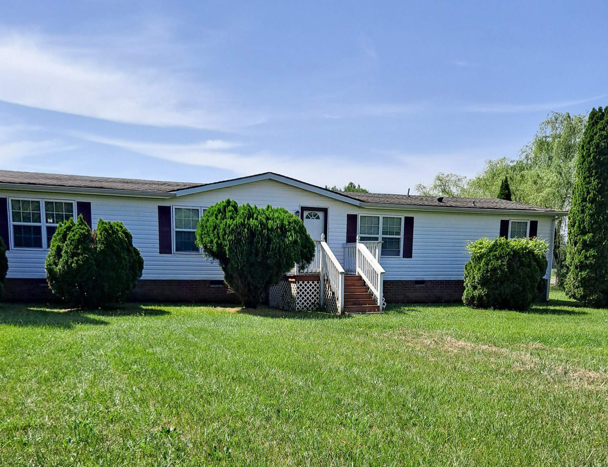 White single‑story home with a front stoop, dark shutters, trimmed bushes, and a large green lawn belonging to Sponsored Residential Provider Sheila Thompson in Montross, Virginia.