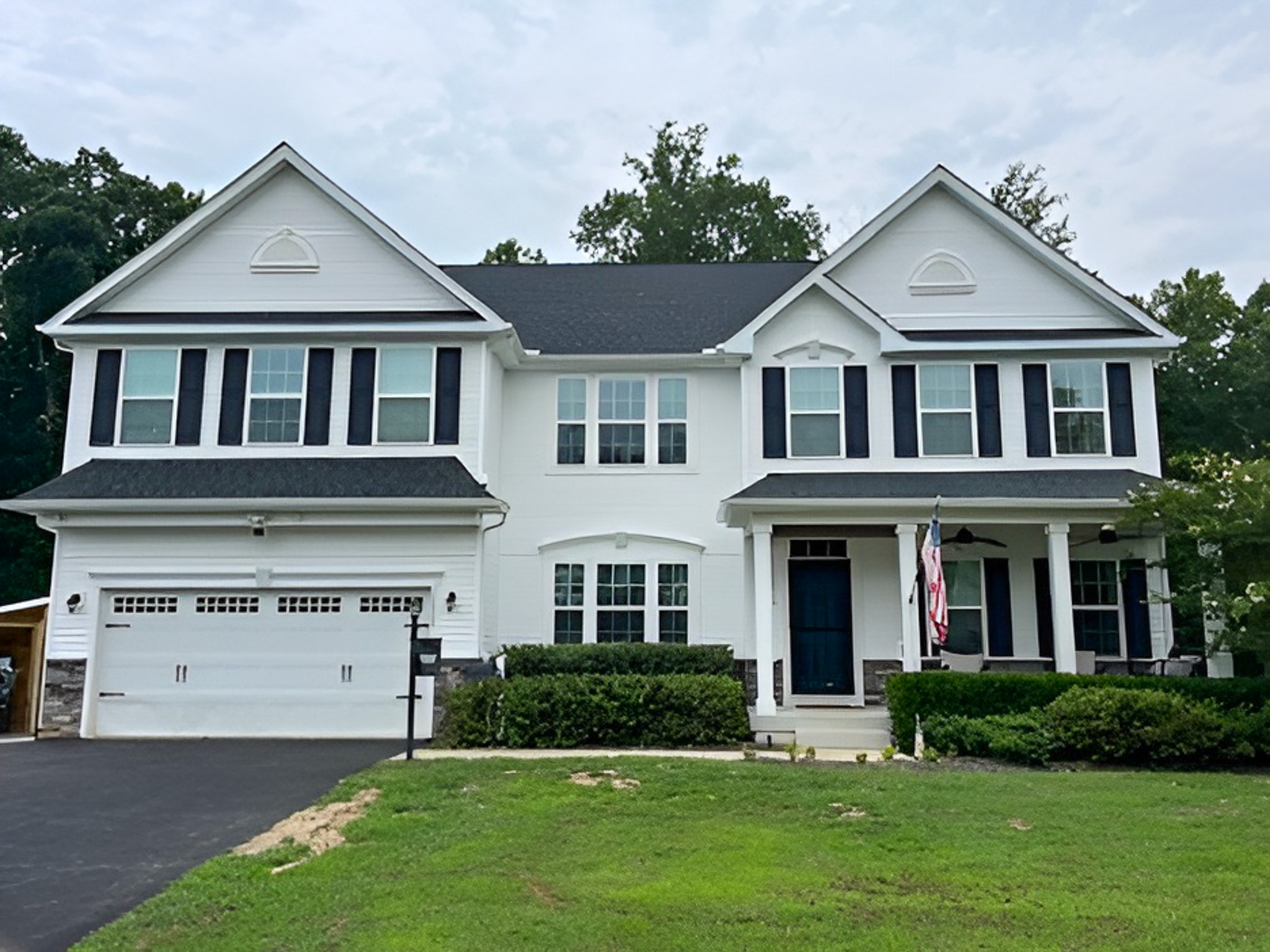 Large two‑story white house with black shutters, a covered porch, and a two‑car garage belonging to Group Home Providers Alex and Dillon Tittle in Fredericksburg, Virginia.
