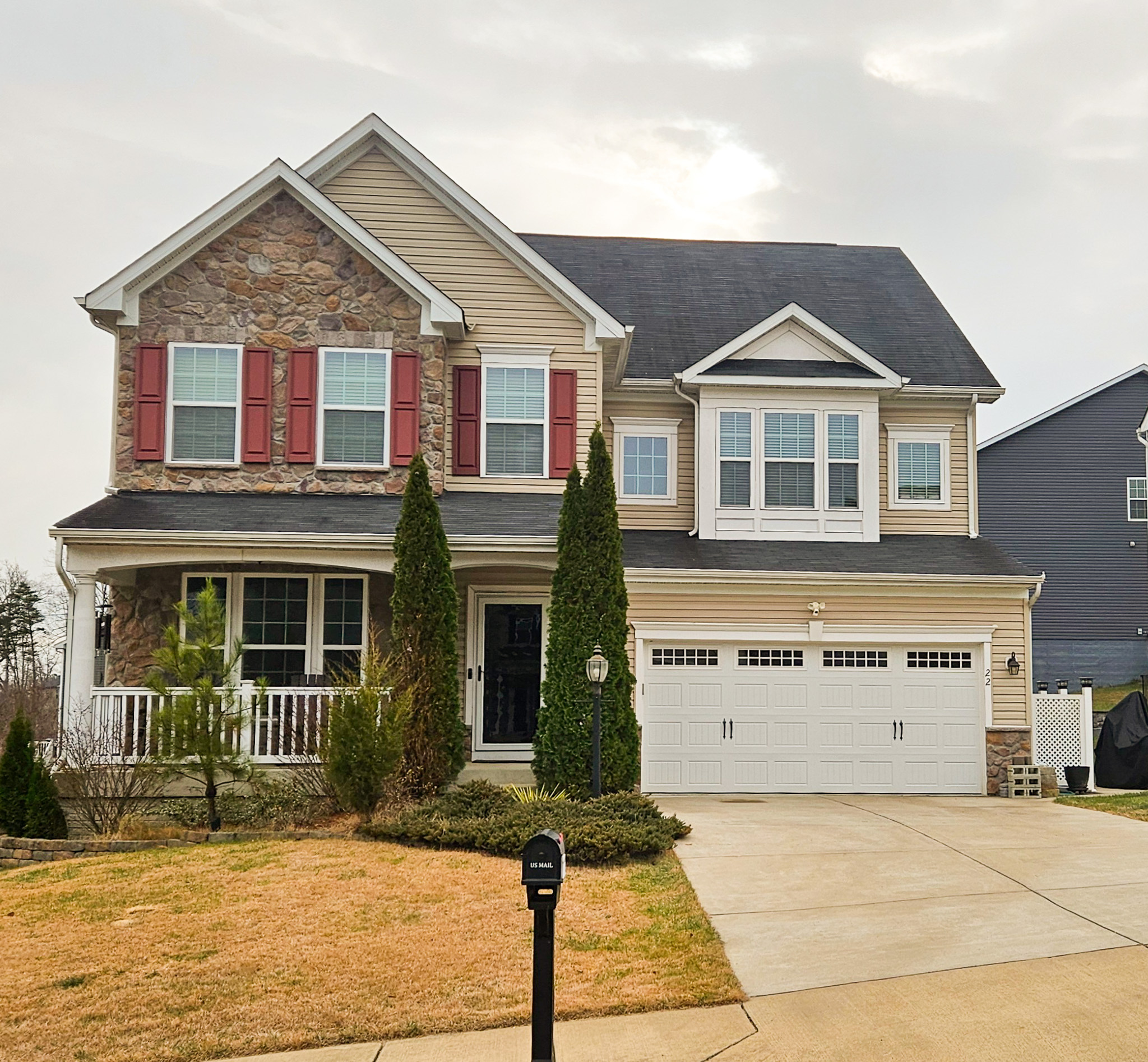 A two‑story suburban house with stone and siding, red shutters, a front porch, and a two‑car garage belonging to Sponsored Residential Provider Vanessa Moore in Fredericksburg, Virginia.