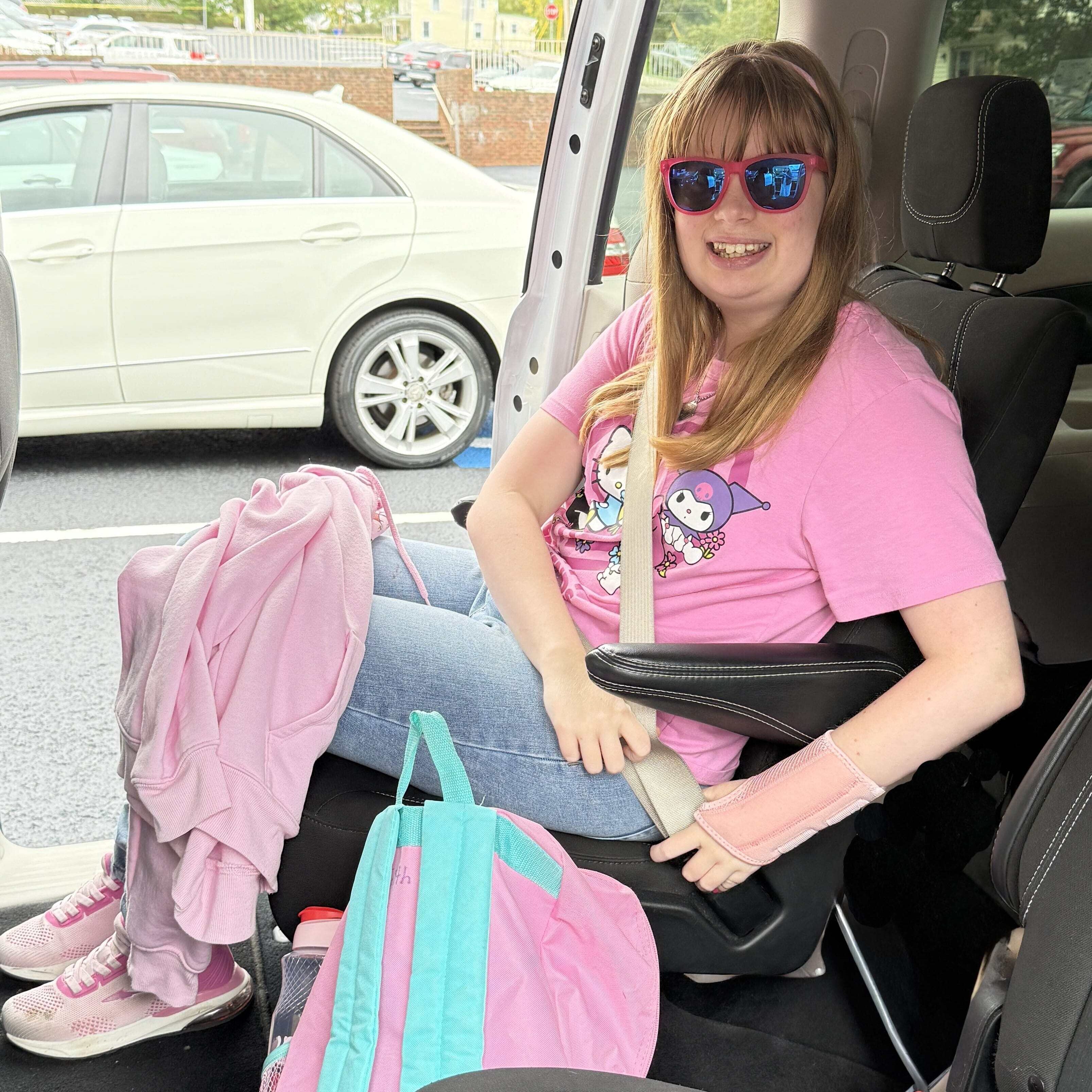 Woman sitting in van smiles as she fastens her seatbelt