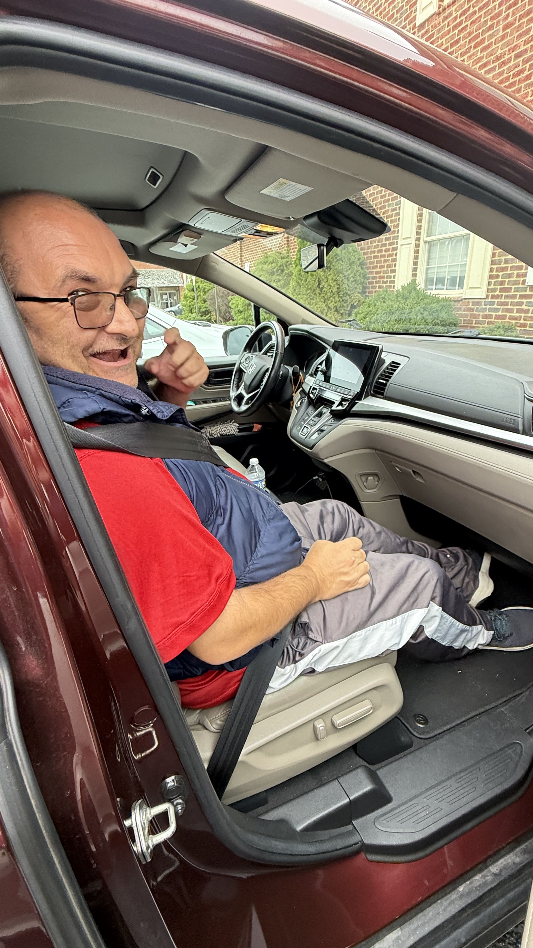 Man smiles and gives a thumbs up from the front passenger seat of a van