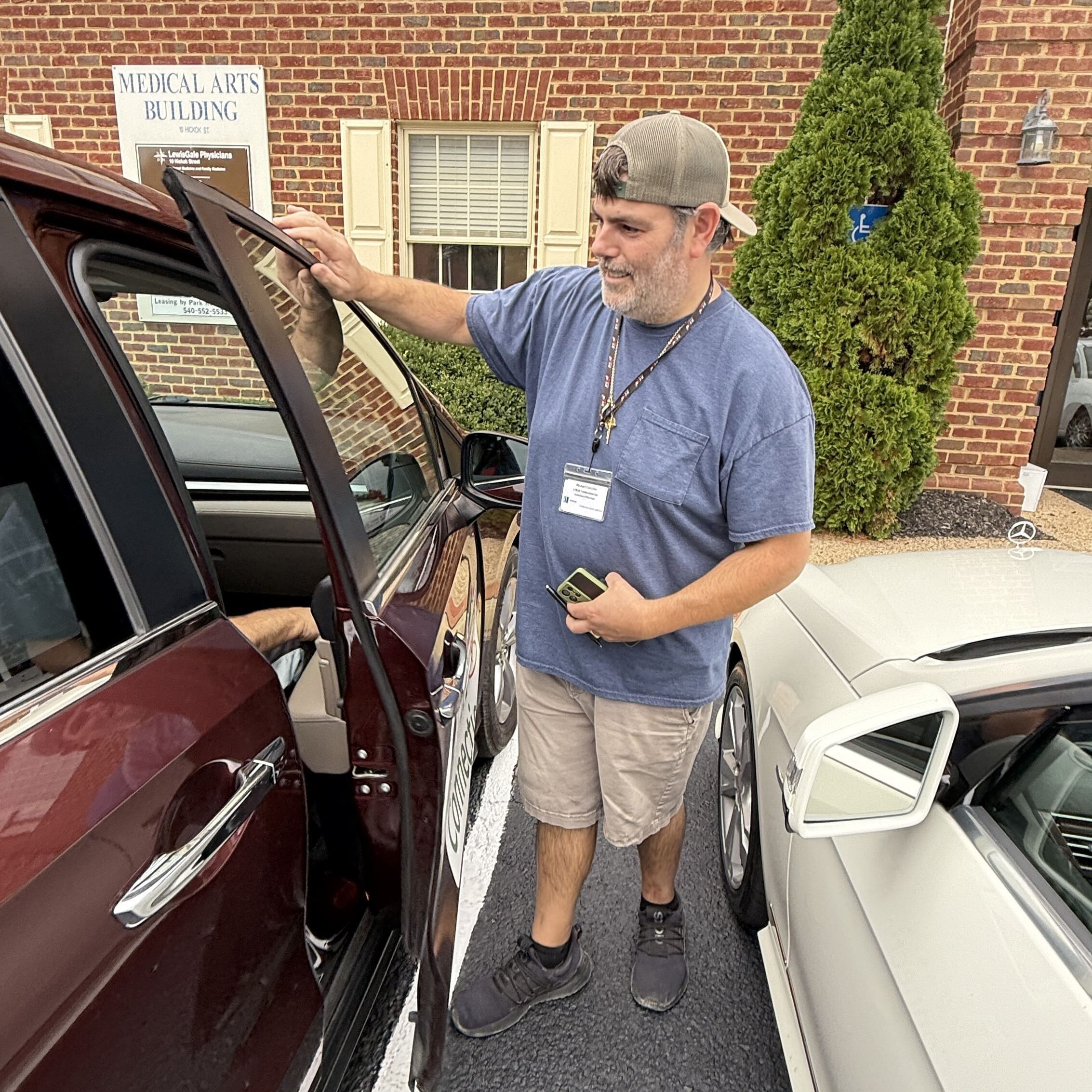 Driver next to passenger side of van talks to a passenger through the car window